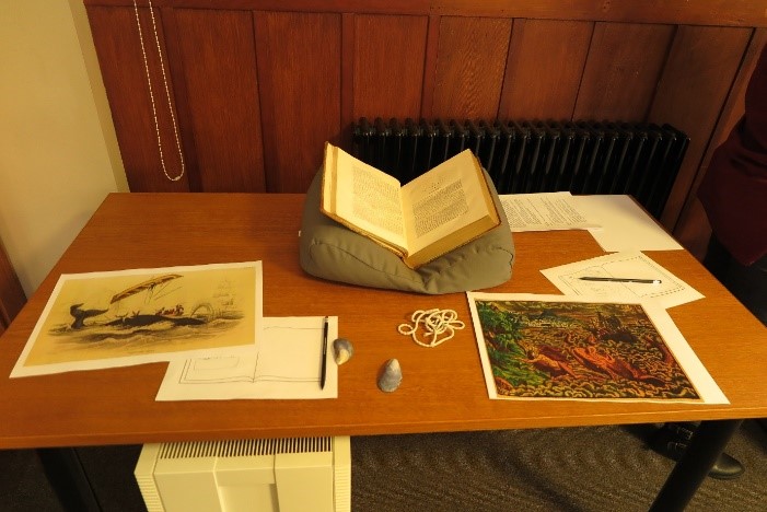 Book open on a table, surrounded by paper and pictures